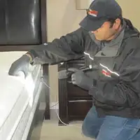Bed bug inspection technician checking a mattress and bed frame for signs of infestation in Albuquerque, NM