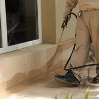 General pest control technician spraying exterior perimeter around a home in Albuquerque, NM