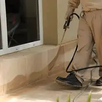 General pest control technician spraying exterior perimeter around a home in Albuquerque, NM