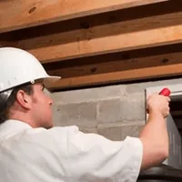 Termite inspection technician checking a basement wall and framing for termite activity in Albuquerque, NM