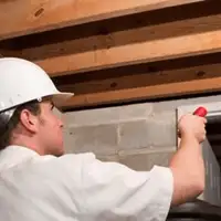 Termite inspection technician checking a basement wall and framing for termite activity in Albuquerque, NM